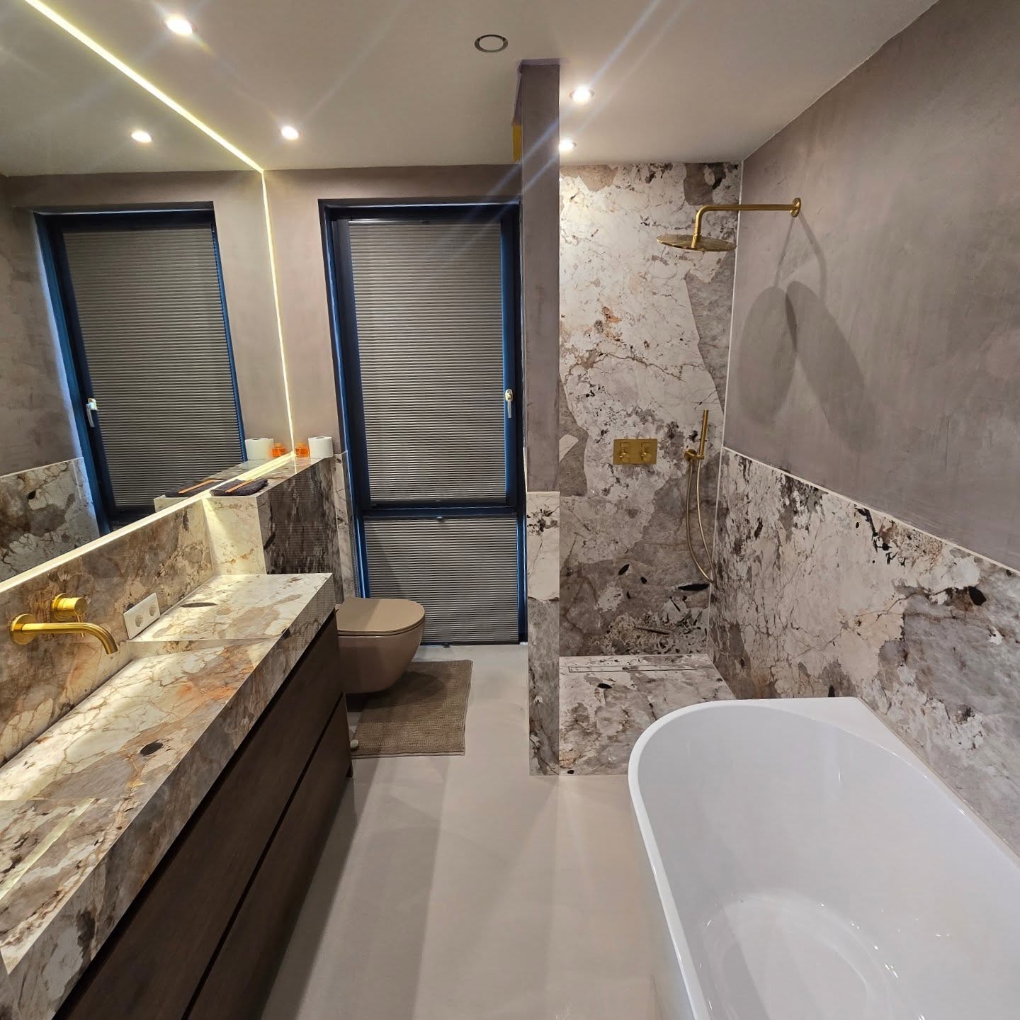 Patagonia slab bathroom by Distinct Bouw, with a bespoke basin, freestanding bath and matching wall surfaces