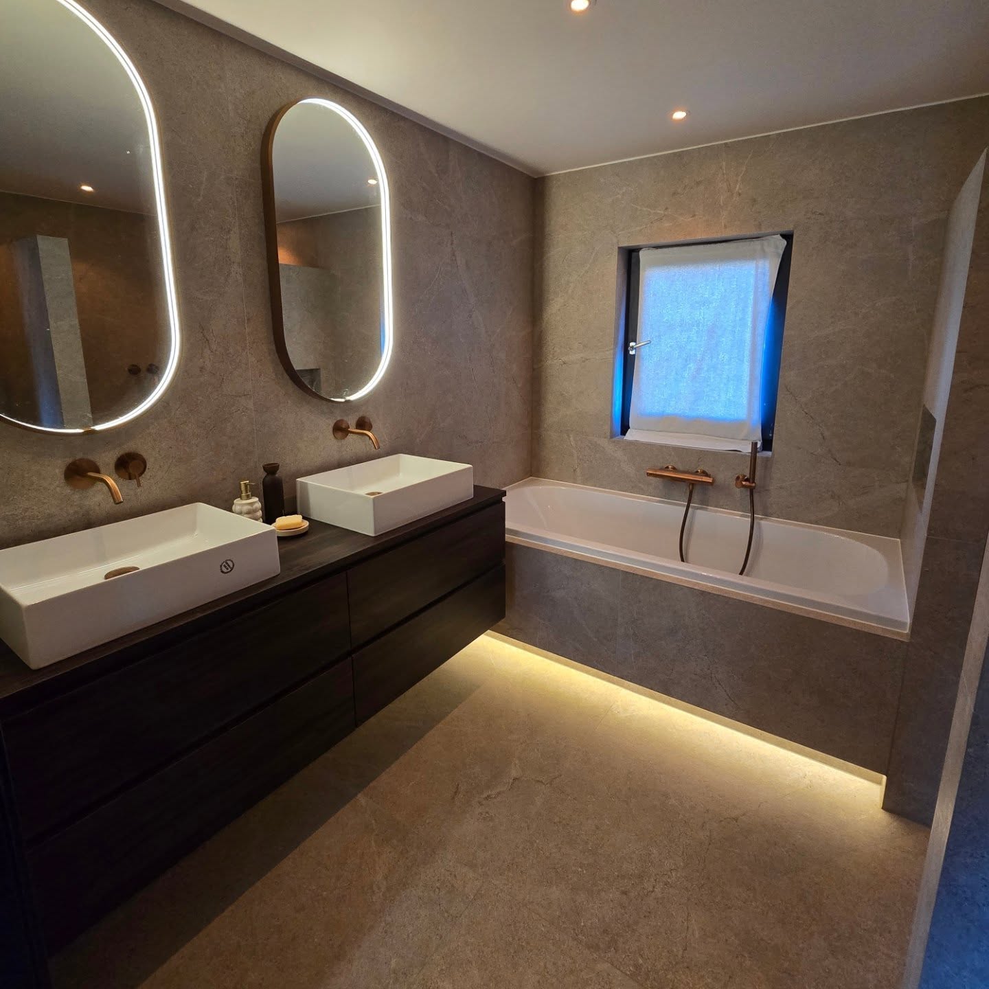 Renovated bathroom with illuminated mirrors, double basins and a built-in bath